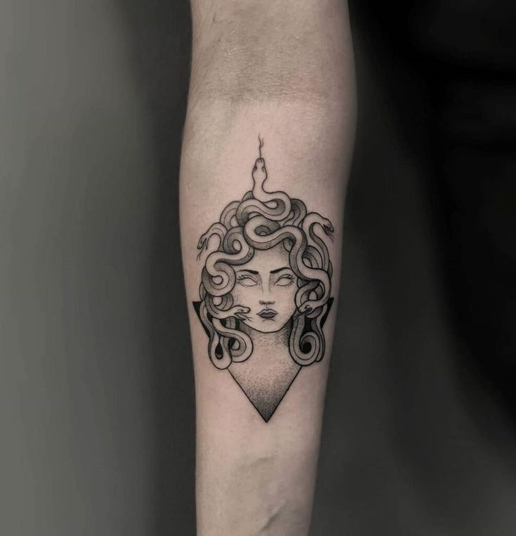 a woman's face with curly hair and a candle tattoo on the left forearm