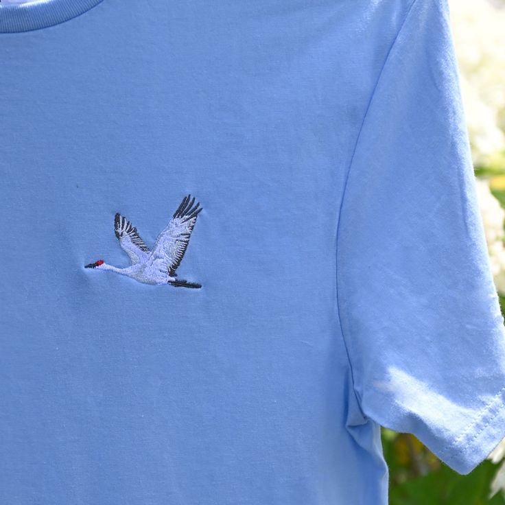 a blue t - shirt with a bird embroidered on it