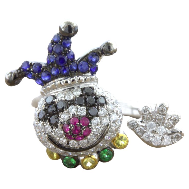 A fun and friendly clown studded in diamonds and colored gemstones. The smiling clown features 0.90 carats of white and black diamonds making its face, eyes, and hand along with 0.48 carats of rubies and sapphires which make its hat and nose. It has a collar of green and yellow gemstones to finish his outfit. Made in 18k white gold and ready to be worn! Ring Size 7.75 Weight: 6.4 grams Colored Gemstones, Yellow Gemstones, Black Diamonds, Gemstone Colors, Black Diamond, Fashion Rings, Ruby, White And Black, Jewelry Rings