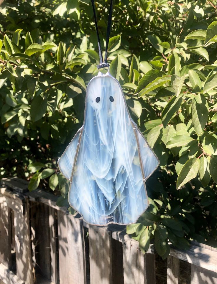 a glass ghost hanging from a wooden fence