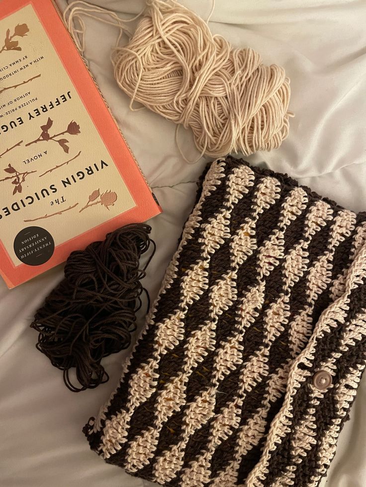 a book and yarn are laying on a bed