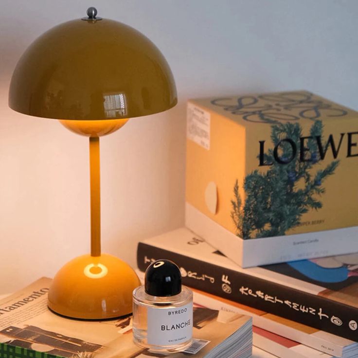 a yellow lamp sitting on top of a table next to books and a book bag