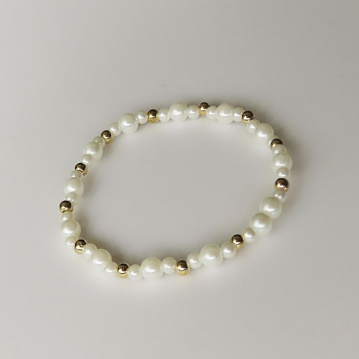 This delicate bracelet features 4mm white glass beads paired with gold spacer beads, creating a classic and elegant look. Measuring 6.5 inches, it's perfect for adding a subtle touch of sophistication to any outfit Elegant Stretch Bracelet With Tiny Beads, Classic White Beaded Stretch Bracelet, Classic White Stretch Bracelet For Everyday, White Adjustable Classic Stretch Bracelet, White Classic Adjustable Stretch Bracelet, Classic Adjustable Beaded Bracelets With Gold Beads, Classic Beaded Bracelets With Adjustable Gold Beads, Elegant White Stretch Bracelet With 8mm Beads, Classic Adjustable Pearl White Beaded Bracelets