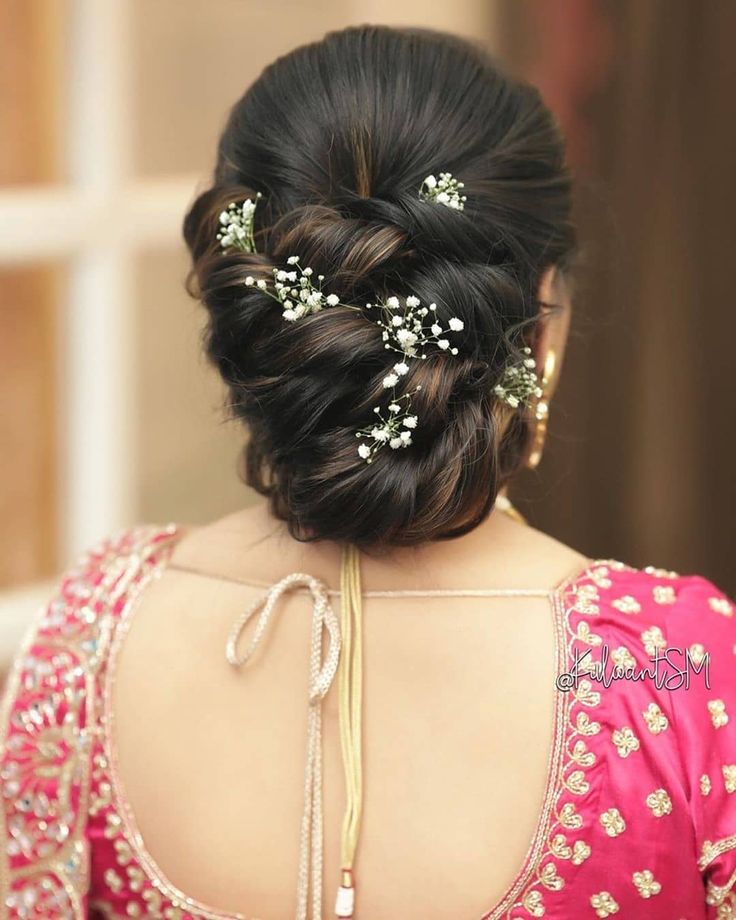 the back of a woman's head with flowers in her hair, wearing a pink blouse