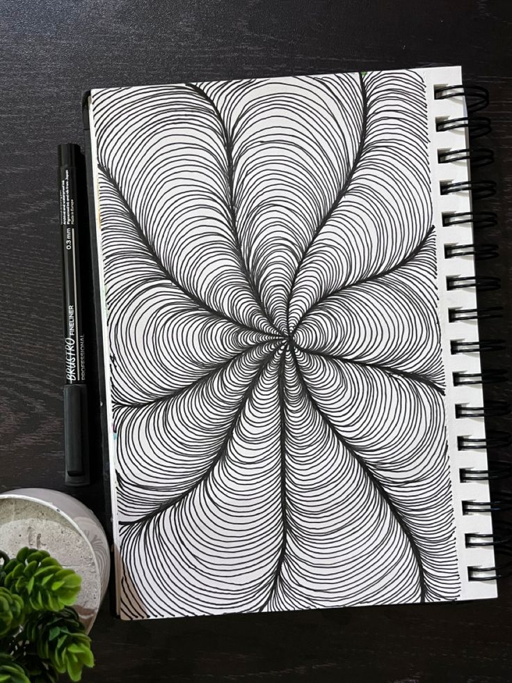 an open spiral notebook sitting on top of a table next to a plant