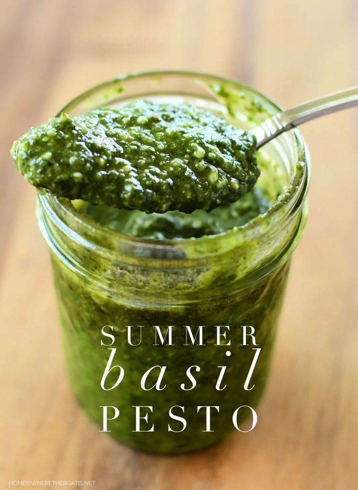 a jar filled with pesto sitting on top of a wooden table