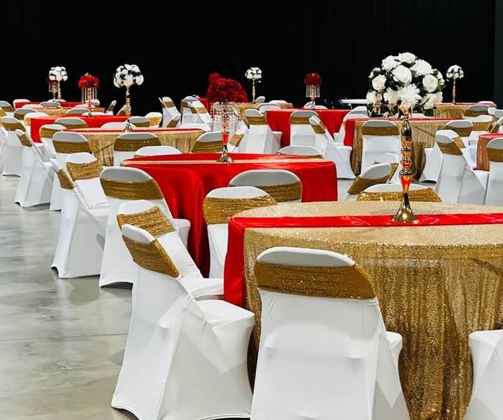 tables and chairs are set up with gold sequin tablecloths, red sashes, and white flowers