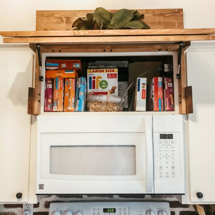 an open microwave oven with cereal and milk on it's shelf above the stove