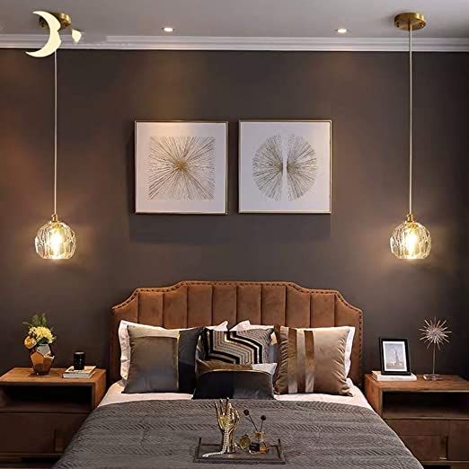 a large bed sitting under two lamps in a bedroom next to a wall with pictures on it