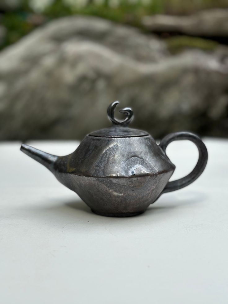 a silver teapot sitting on top of a white table