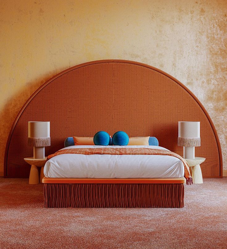 a bed with two lamps on either side and an orange headboard in the background