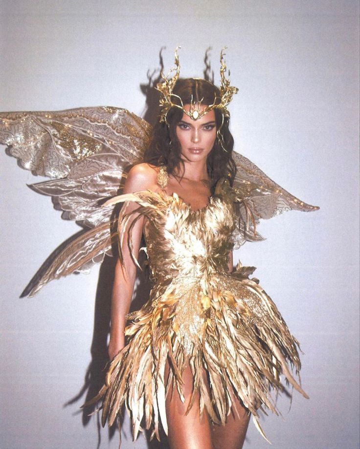 a woman in a gold dress with wings on her head