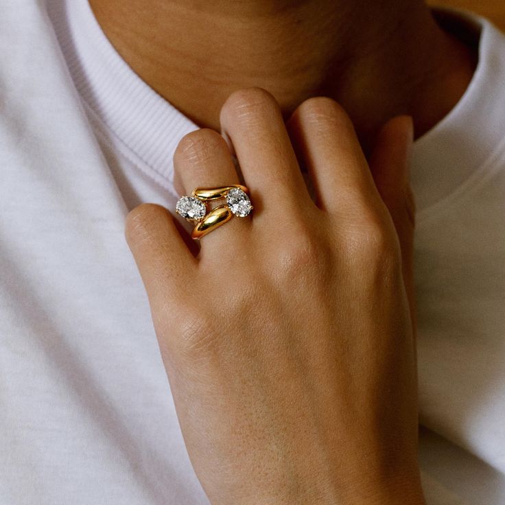 a close up of a person wearing a gold ring with two diamonds on the middle