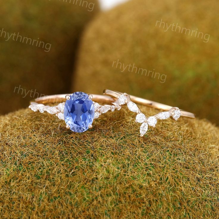 a ring with an oval blue stone surrounded by smaller white stones on top of moss