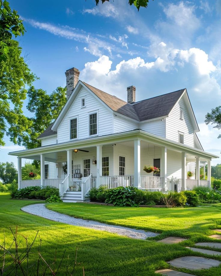 a large white house sitting in the middle of a lush green field on a sunny day