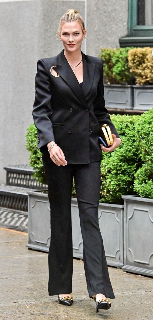 the woman is walking down the street in her black suit