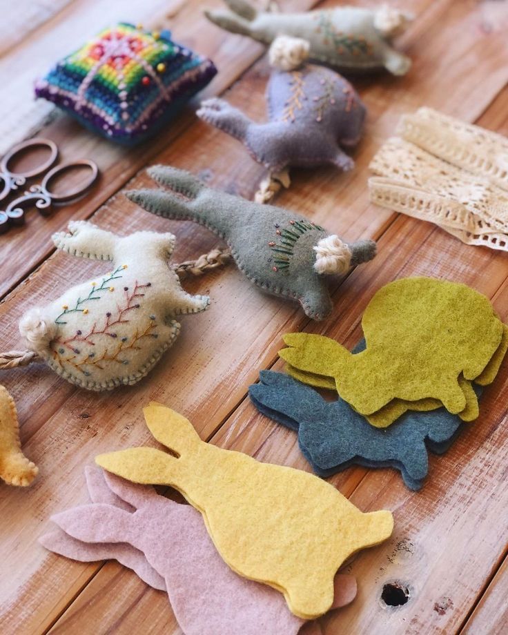 several felt animals sitting on top of a wooden table next to scissors and other crafting supplies