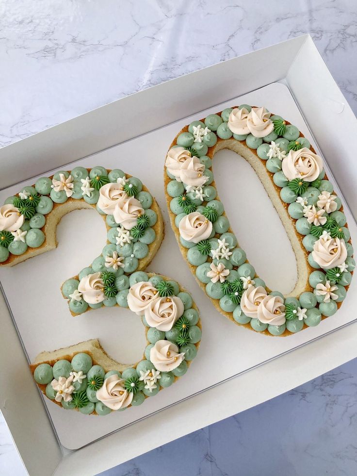 a cake in the shape of a number 30 decorated with flowers and greenery on top