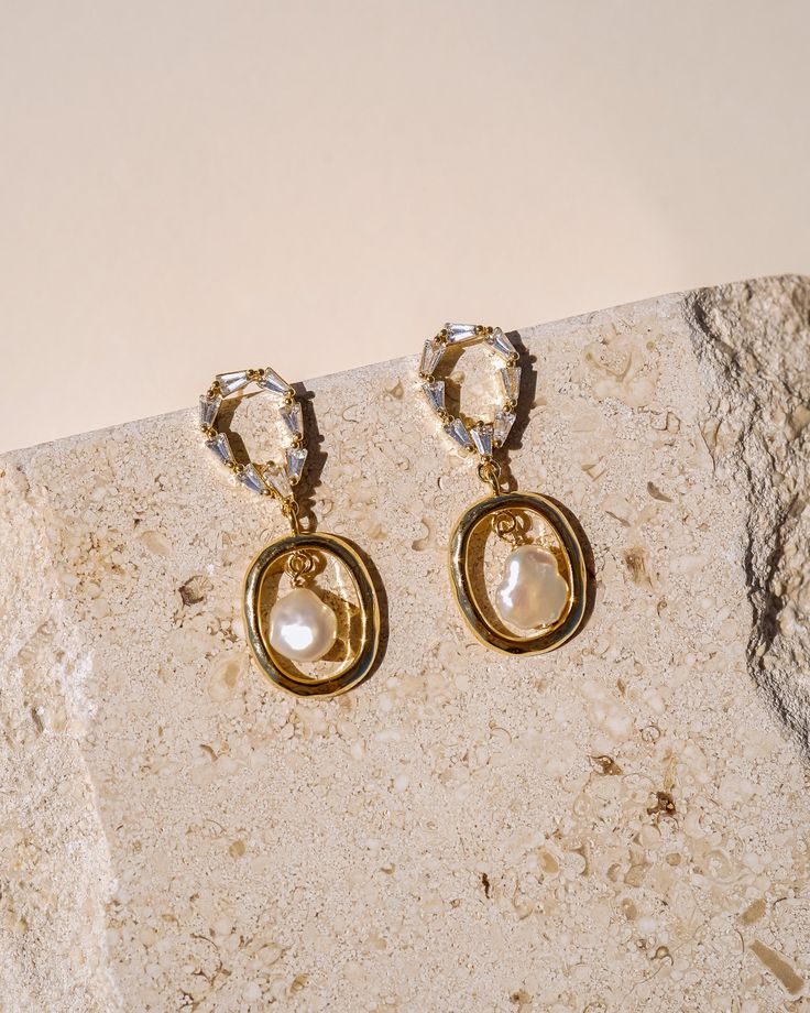 Introducing our stunning Cassie Pearl Drop Earrings - the perfect accessory for any occasion! These exquisite earrings are designed to add a touch of glamour and sophistication to your look, with their delicate pearl drops and luxurious gold finish. The pearls are carefully selected for their radiance and beauty, creating an iridescent effect that is sure to catch the eye! The gold finish and pearl detailing adds an extra touch of elegance creating a look that is both classic and modern. EARRING Gold Pearl Pendant Dangle Earrings, Chic Gold Pearl Earrings, Chic Gold Bridal Earrings With Pearl, Glamorous Pearl Earrings As Gift, Gold Teardrop Earrings With Pearl Charm, Chic Gold Pearl Earrings With Pearl Pendant, Gold Plated Dangle Earrings With Pearl Pendant, Glamorous Pearl White Pearl Drop Earrings, Gold Plated Gold Earrings With Pearl Chain