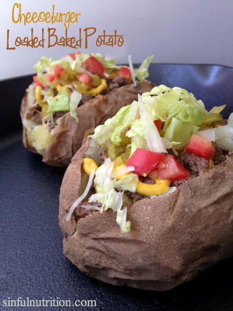 two baked potatoes with lettuce and tomatoes on them sitting on a black plate