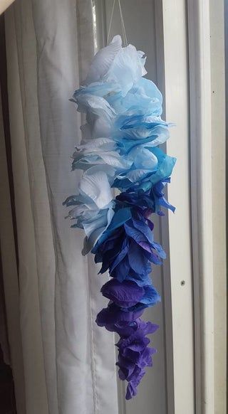 some blue and purple tissue paper flowers hanging from a window