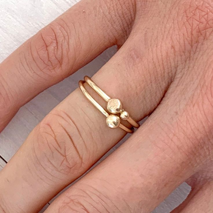 A dainty minimalist ring with two gold balls perched on top of a 1.5mm gold band in 100% recycled gold, this is the perfect ring for a lover of all things delicate and understated. With a small bead leaning against the larger one, these gold balls resemble a mother and baby nestled against each other, thus making this ring a perfect gift for a mum. Both gold balls have a flatter, textured side, adding some interest to an otherwise perfectly geometric piece of jewellery. Made in solid gold, this Minimalist Stackable 14k Gold-filled Toe Rings, Minimalist 14k Gold-filled Stackable Toe Rings, Minimalist 14k Gold Filled Stackable Toe Rings, Minimalist 14k Gold-filled Midi Toe Rings, Minimalist Recycled Gold Stackable Toe Rings, Minimalist 14k Gold Filled Midi Toe Rings, Minimalist Stackable Midi Rings In Recycled Gold, Minimalist Stackable Recycled Gold Midi Rings, Minimalist Stackable Rings In Recycled Gold