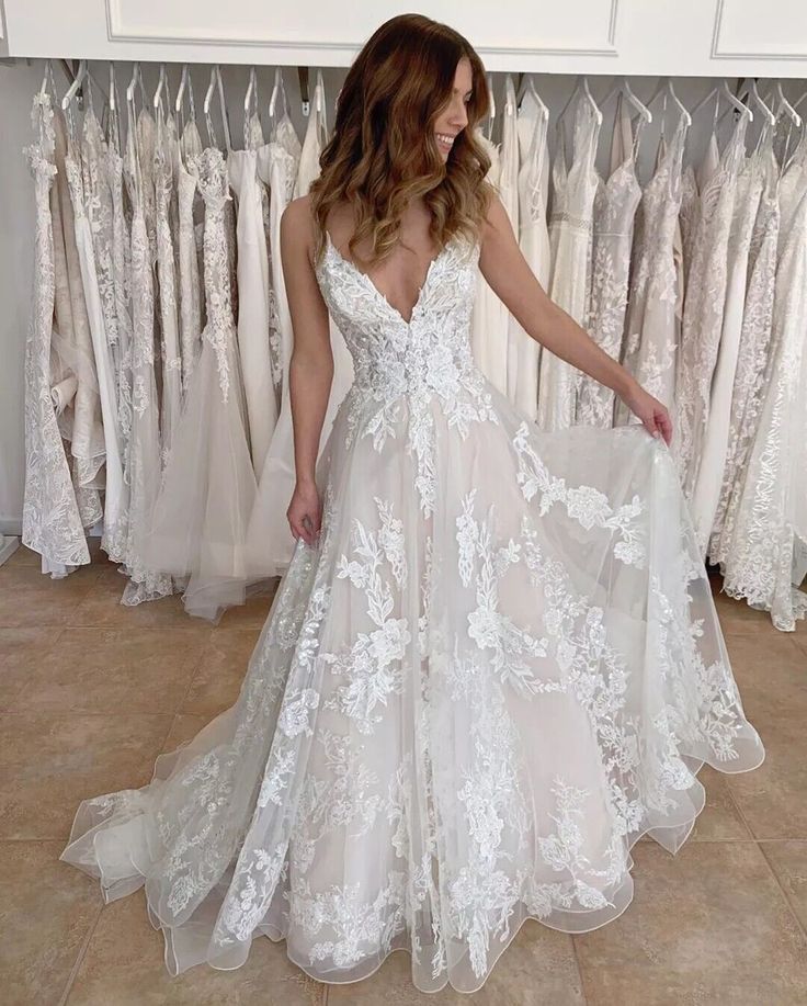 a woman in a white wedding dress standing next to a rack of brides dresses