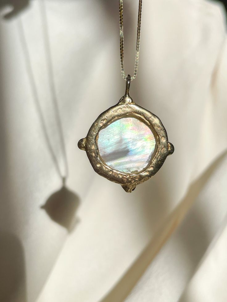 A dreamy 15mm hand-carved Mother of Pearl Moon encircled in gold, set with (4) White Diamonds, set on a solid 14k yellow gold 0.8mm box chain. (Approx. 5.7g.) Inspired in essence by the Impressionist French composer Claude Debussy, Clair de Lune translates to pale blue light or moonlight, and embodies the Divine Feminine energy of the moon, wholly encapsulating the deep sense of serenity found through inner self-awareness, and the strength kept within the gentleness of the heart. Aligns with int Celestial Jewelry With Coin Pendant For Anniversary, Heirloom Style Recycled Gold Jewelry, Heirloom Recycled Gold Round Jewelry, Celestial Medallion Jewelry For Anniversary, Celestial 14k Gold Coin Pendant Jewelry, Celestial 14k Gold Round Pendant Jewelry, Unique Round Pearl Pendant Jewelry, White Gold Brass Jewelry With Round Shape, Heirloom Crescent Jewelry For Gifts