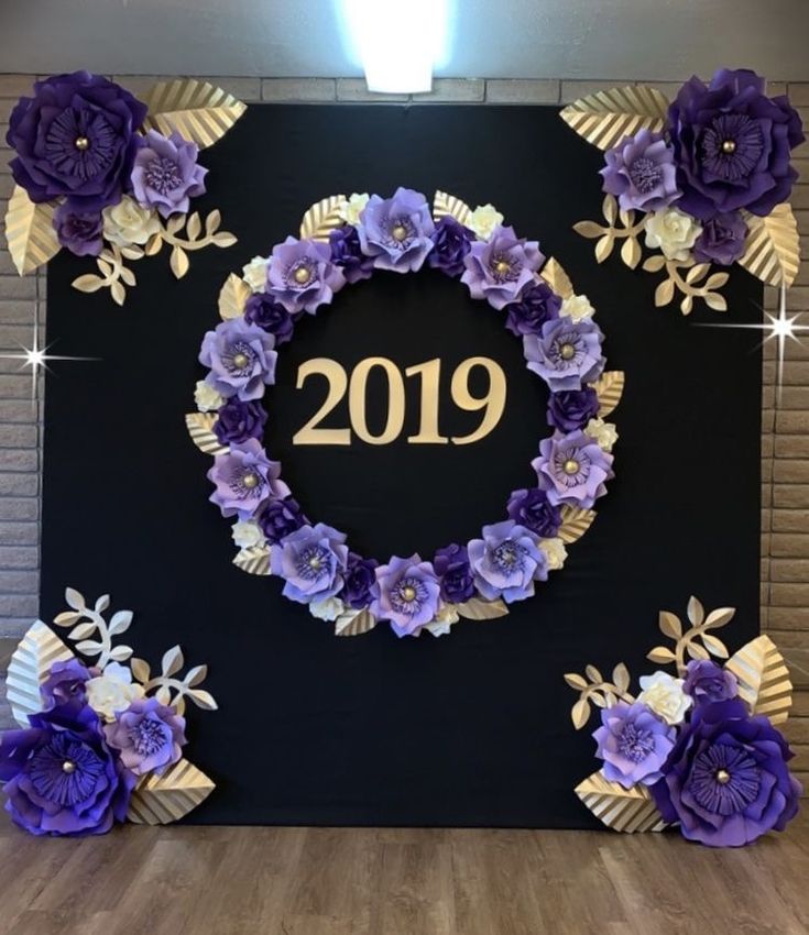 purple paper flowers are arranged around the year 2019 on a black backdrop with gold leaves