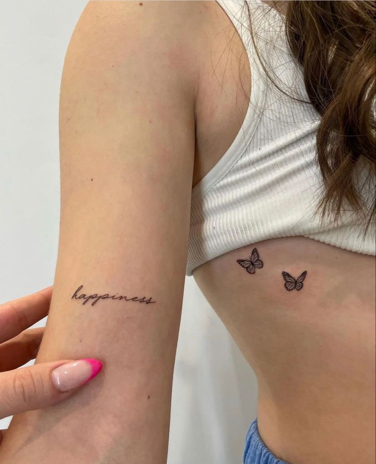 a woman's left arm with a small tattoo on it that says happiness and butterflies