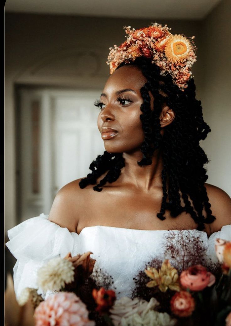 a woman with flowers in her hair standing next to a vase filled with orange and pink flowers