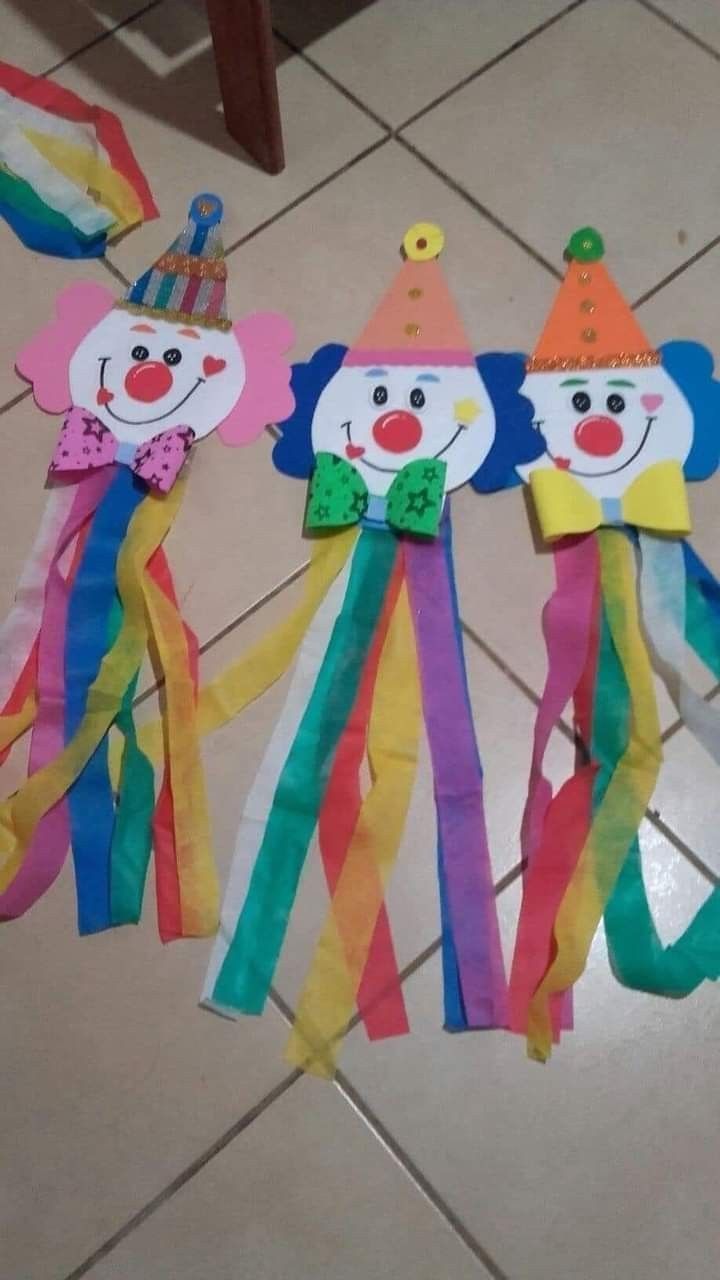 three colorful kites with clown faces on them sitting on the floor next to each other