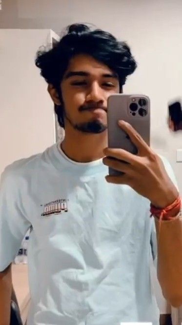 a man taking a selfie with his cell phone in the mirror while wearing a white t - shirt