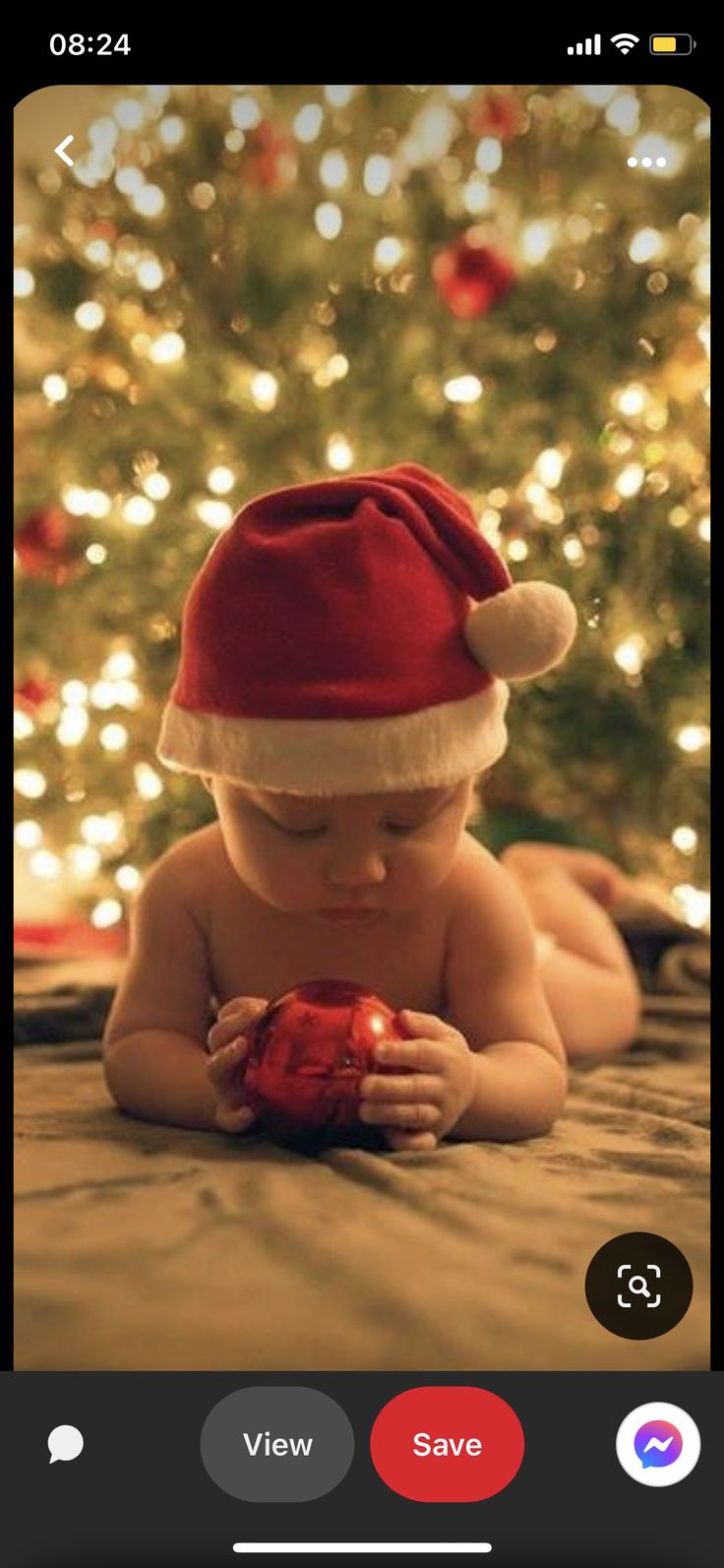 a baby wearing a santa hat sitting in front of a christmas tree