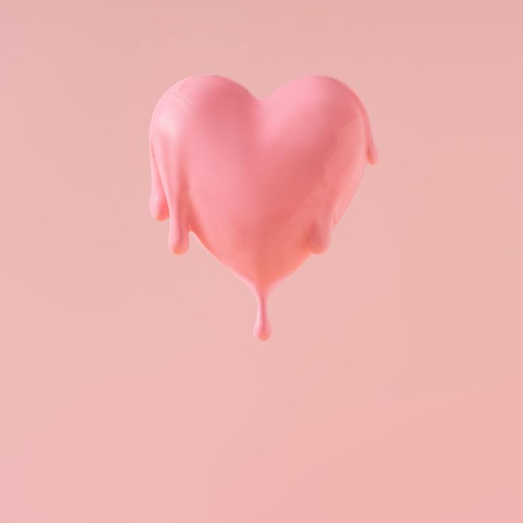 a pink heart shaped lollipop with dripping liquid on it's side against a light pink background