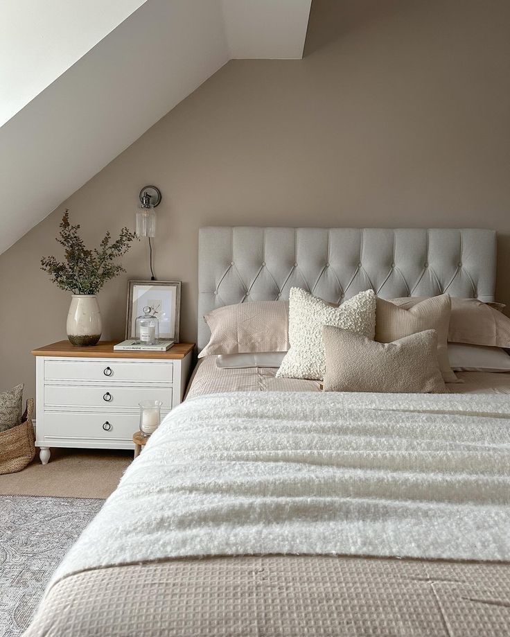 a large bed sitting under a skylight next to a white dresser and lamp on top of a wooden table