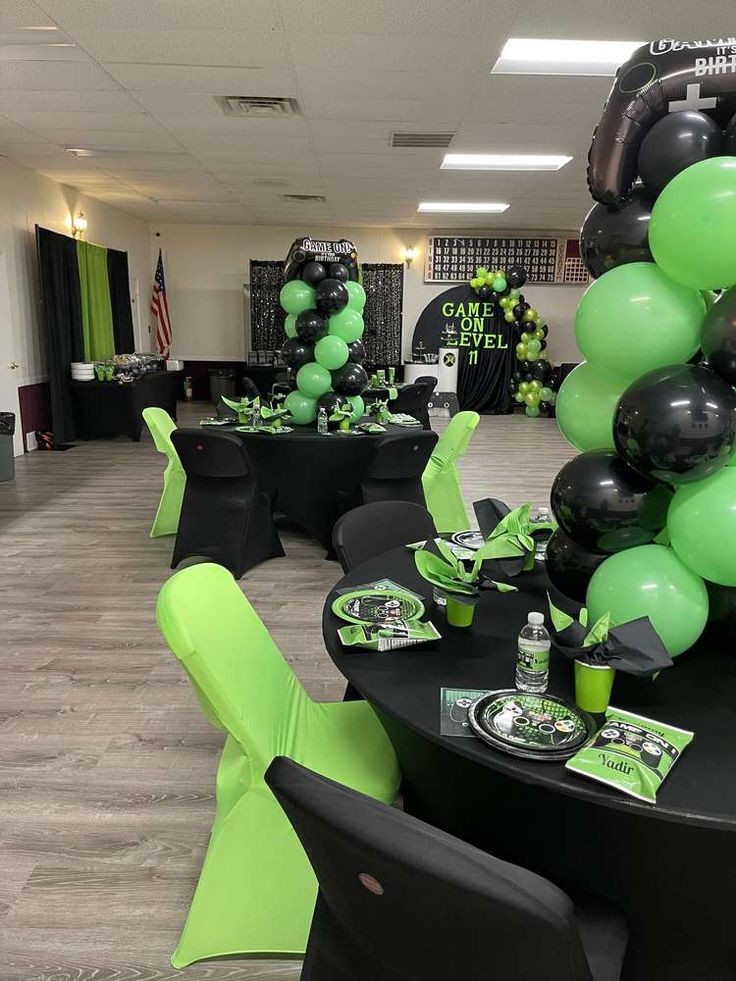 a room filled with black and green balloons