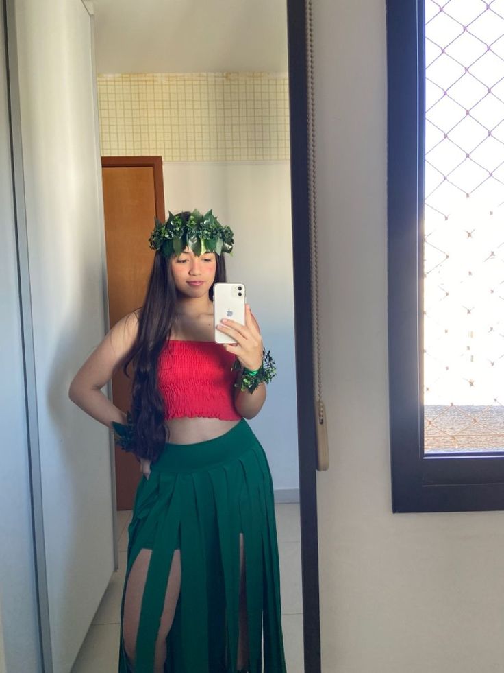 a woman taking a selfie in a mirror wearing a green skirt and red top