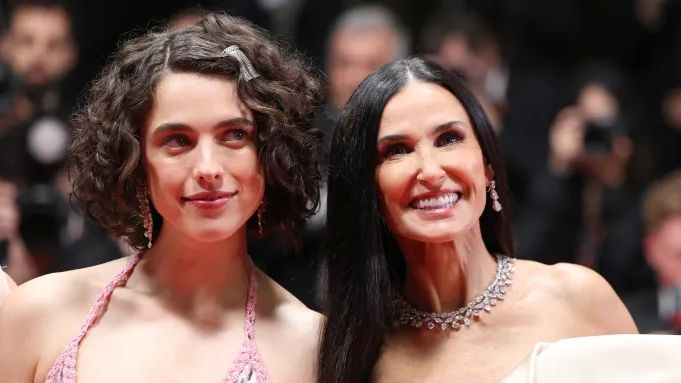 two women standing next to each other in front of a crowd at a red carpet event