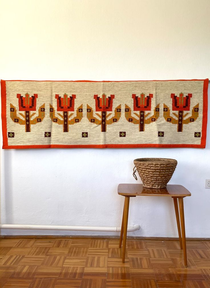 a basket sitting on top of a wooden table next to a wall hanging