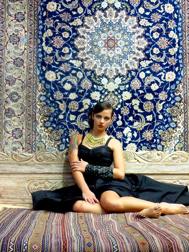 a woman sitting on top of a bed in front of a rug