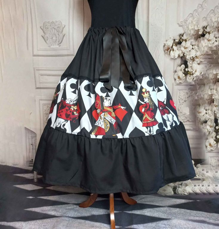 "\"Step into the fantastical world of Alice in Wonderland with this beautiful, handcrafted skirt featuring a stunning print inspired by Lewis Carroll's classic tale in vivid red, gold, black and white. The full skirt design adds a touch of whimsy and elegance, making it the perfect addition to any wardrobe.  Whether you're dressing up for a special occasion or adding a touch of Alice to your everyday look, this skirt is sure to make a statement. Order yours today and let the adventures begin!\" Featuring the  Queen of Hearts and Queen Alice, the White Rabbit and other delightful characters from the Lewis Carroll classic.  This longer length skirt is great for casual wear or even an office party.  Dress it up with long boots or simple sandles in hotter weather.   A delightfully swishy full Fantasy Black Skirt For Costume, Fantasy Costume Black Skirt, Fantasy Skirt For Halloween Costume Party, Fitted Fantasy Skirt For Fantasy Events, Fitted Fantasy Skirt For Costume Party, Black Costume Skirt With Attached Cancan, Black Skirt With Attached Cancan For Costume, Fitted Fantasy Black Skirt, Fitted Skirt For Cosplay Events