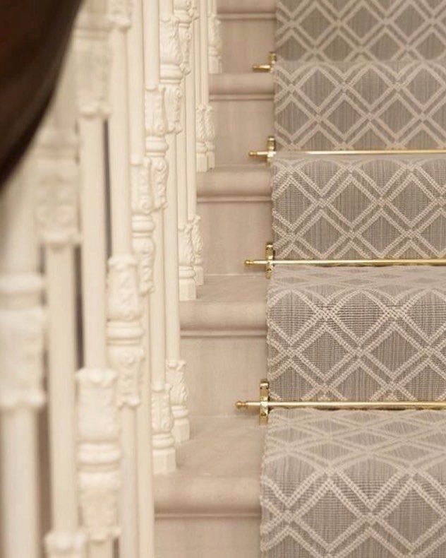 the stairs are lined with decorative wallpaper and gold rods on each handrails