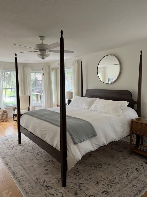 a bedroom with a four post bed, dresser and large mirror on the wall above it