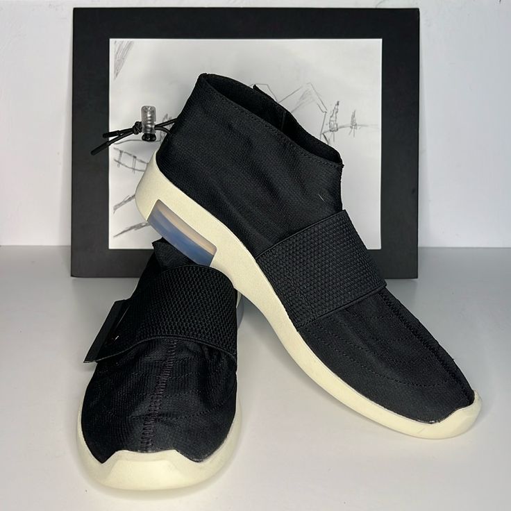 The Nike Air X Fear Of God Strap Looks To Nikes Past Ventures, As The Moccasin Style Offering Gets Outfitted With A Midfoot Velcro Strap, A Magnetic Snap Button Closure And An Adjustable Clear Heel Toggle. Double Stacked Zoom Air Technology Is Made Visible At The Heel Of The Nike Air X Fear Of God Strap, Along With A Rubber Midsole Emblazoned With Tonal Branding At The Lateral Side. The Nike Air X Fear Of God Strap Is Made With A Durable Yet Lightweight Nylon Ripstop Fabric. - Nylon Ripstop Uppe Slip-on Walking Shoes With Round Toe For Streetwear, Casual Slip-on Sneakers With Abzorb Midsole, Comfortable Black Sneakers With Contrast Sole, Slip-on Ankle-high Sneakers With Rubber Sole, Casual Black Ankle-high Slip-on Sneakers, Nike Casual High-top Slip-on Sneakers, Casual Nike Low-top Walking Shoes, Casual Low-top Nike Walking Shoes, Comfortable High-top Black Walking Shoes