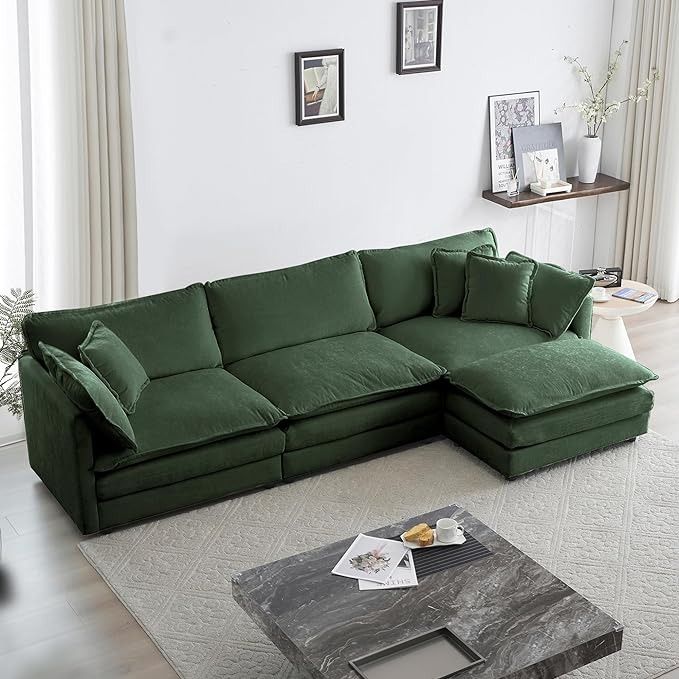 a living room with a large green couch and coffee table in front of the window