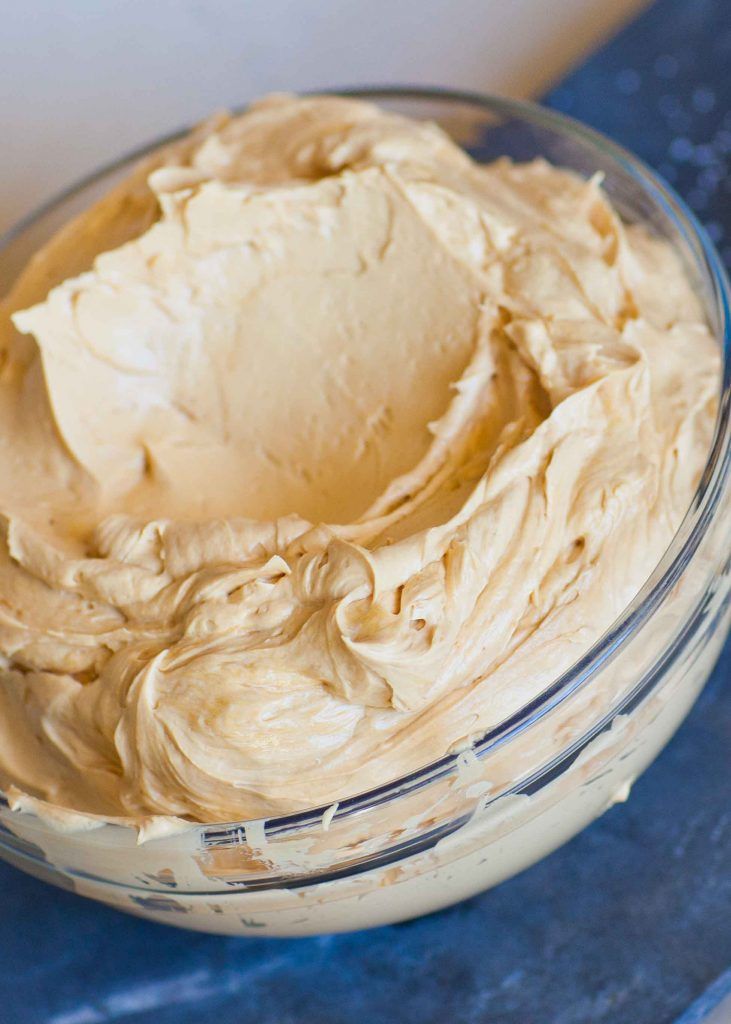 a bowl filled with cream sitting on top of a blue tablecloth next to a knife