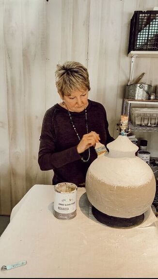 a woman is decorating a large white vase