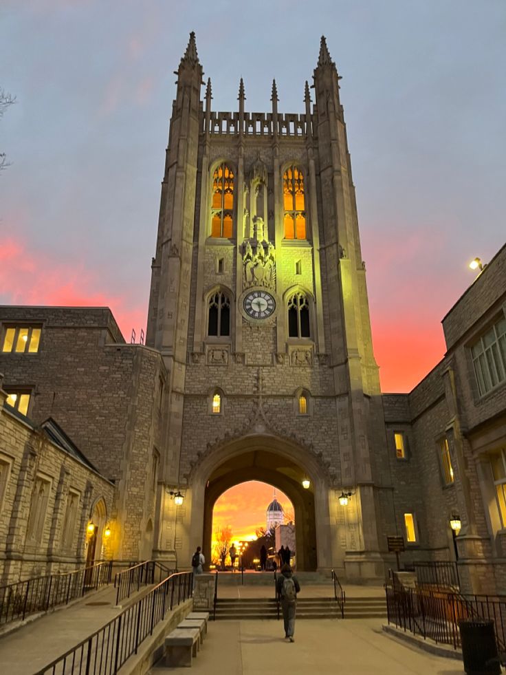 a large building with a clock on it's face and people walking in front