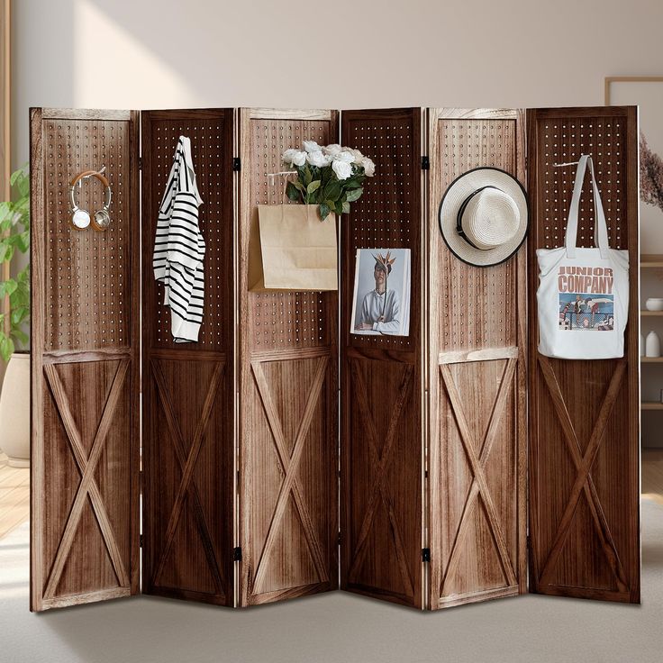 a room divider made out of wood with pictures on the doors and hats hanging from it